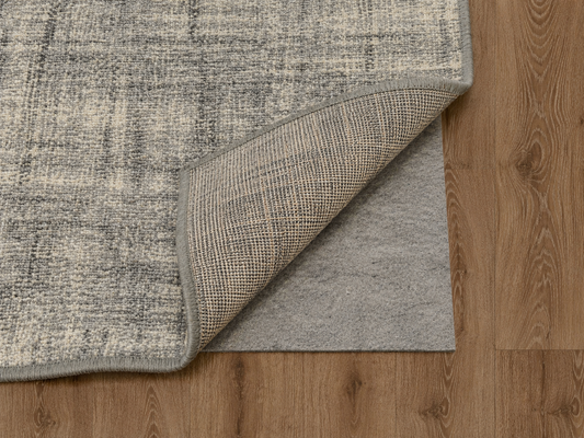 Low-profile all-surface rug pad under an area rug on a hardwood floor