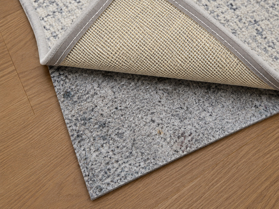 Designer cushioned non-slip rug pad under an area rug on a hardwood floor